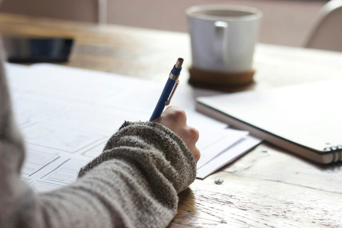 Writing study notes beside a laptop